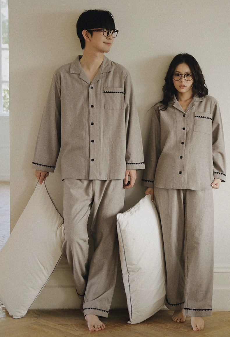 Full-length front view of a couple wearing taupe striped pajamas with black trim