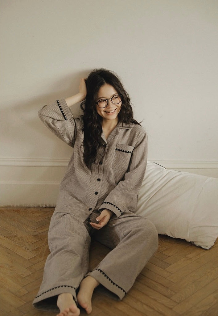 Woman lounging in taupe striped pajamas with contrast trim