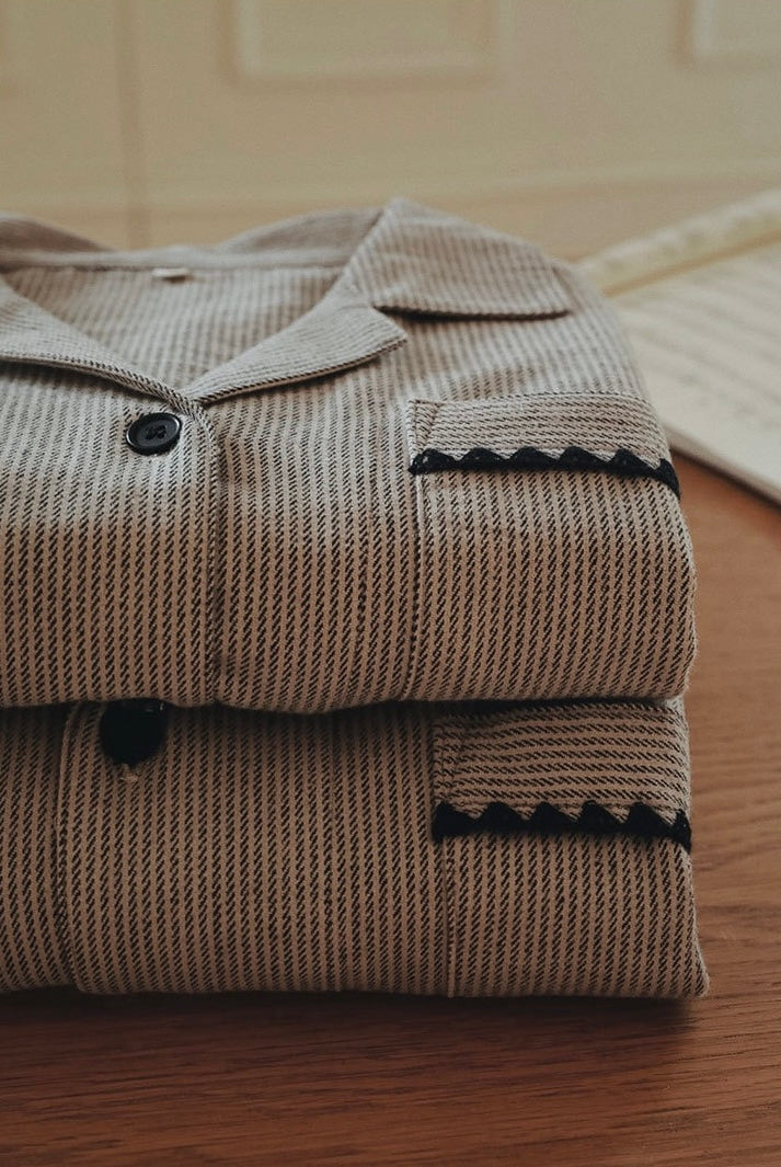 Folded taupe striped pajama tops with dark buttons and black pocket trim